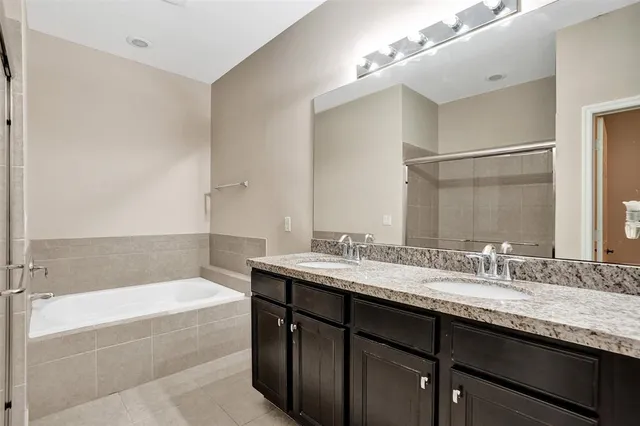 a bathroom with a granite countertop bathtub sink double and mirror