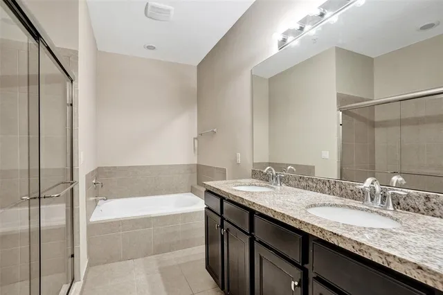 a bathroom with a granite countertop bathtub sink vanity and mirror