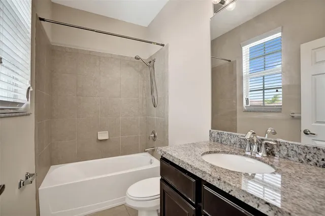 a bathroom with a granite countertop sink toilet tub and shower