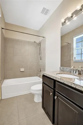 a bathroom with a granite countertop bathtub shower sink vanity and toilet