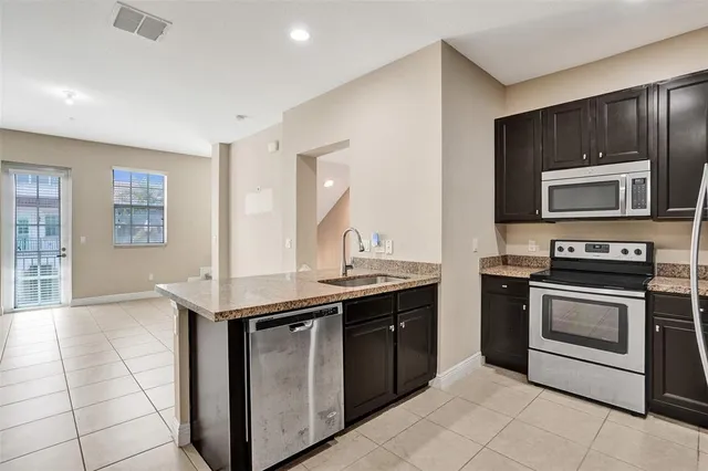 a kitchen with stainless steel appliances granite countertop a stove a sink and a microwave