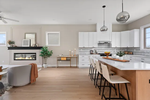 a kitchen with stainless steel appliances granite countertop a stove a sink a refrigerator and a dining table with wooden floor