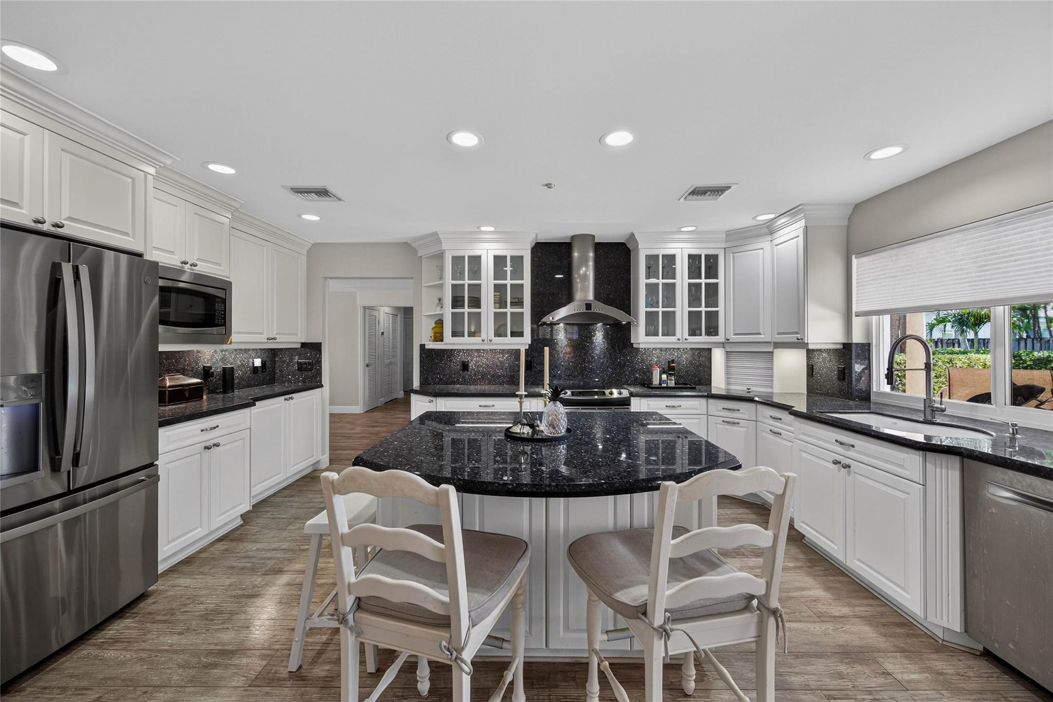 2600 Northeast 46th Street Lighthouse Point, FL 33064 - Photo 14 of 59 a kitchen with stainless steel appliances granite countertop a stove a sink a refrigerator white cabinets and couches with wooden floor