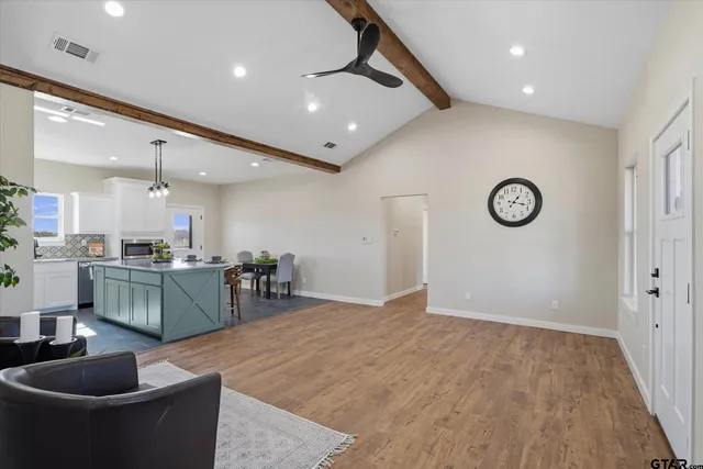 a kitchen with stainless steel appliances kitchen island granite countertop a refrigerator a sink a stove and a wooden floors