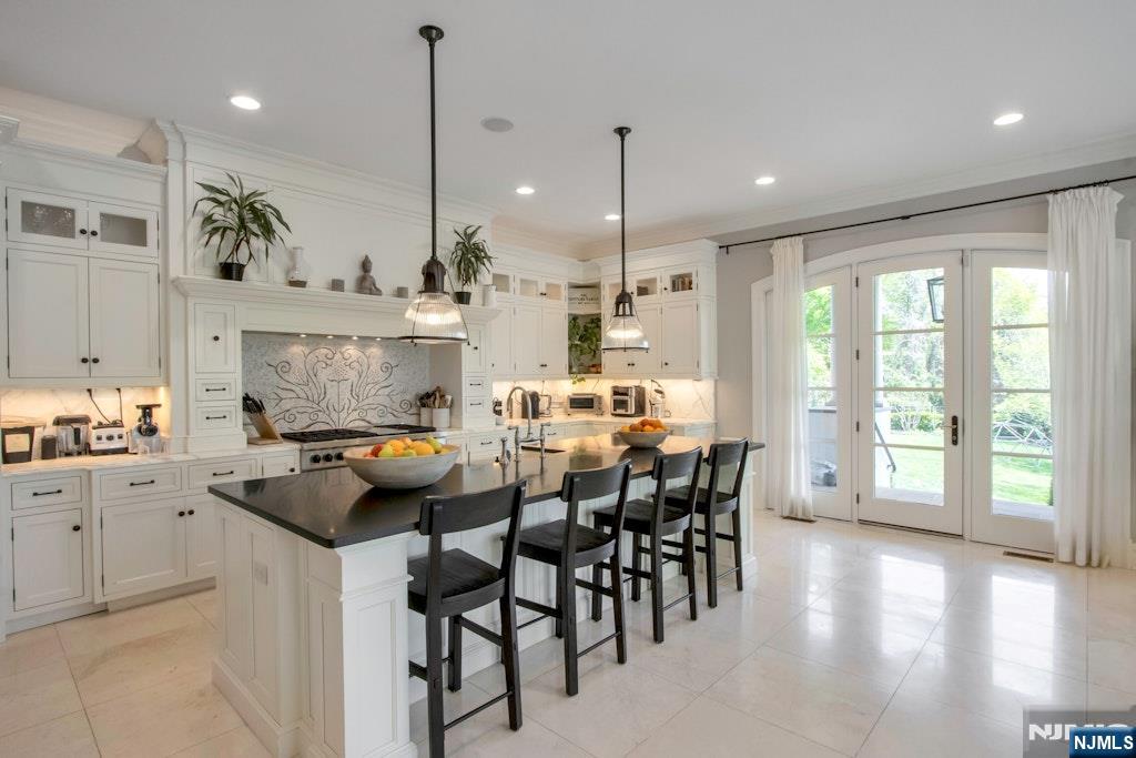 19 Autumn Terrace Alpine, NJ 07620 - Photo 15 of 33 a kitchen with stainless steel appliances kitchen island granite countertop a stove a sink a oven a dining table and chairs with wooden floor