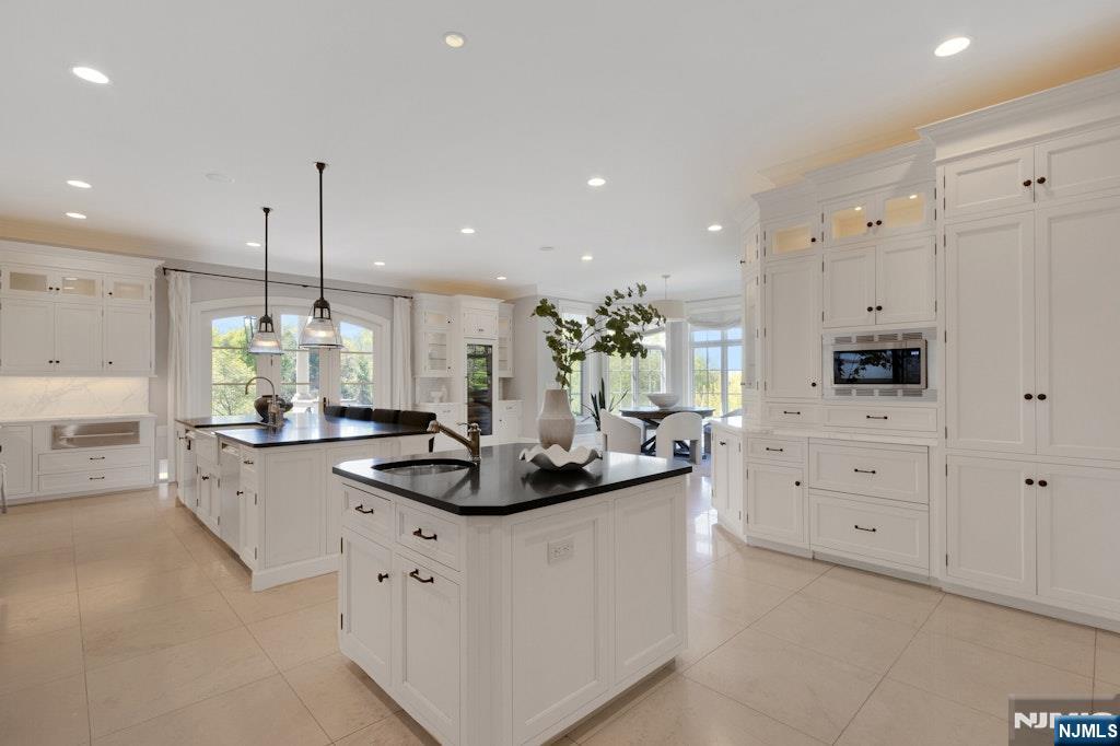 19 Autumn Terrace Alpine, NJ 07620 - Photo 18 of 45 a kitchen with white cabinets and chandelier