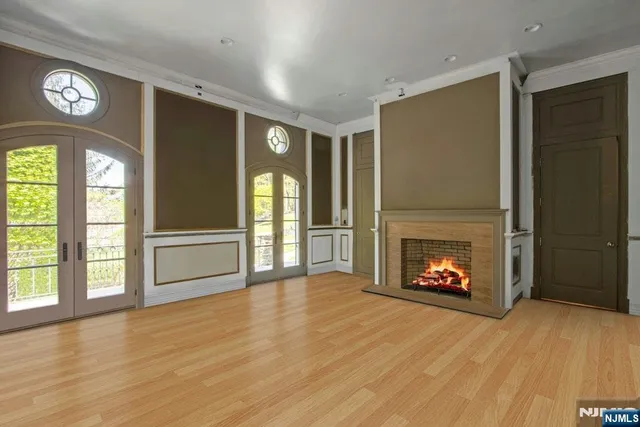 a view of an empty room with wooden floor fireplace and a window