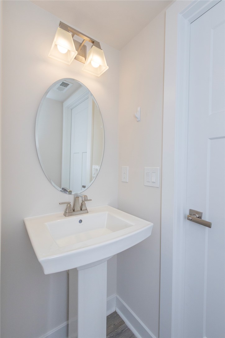 233 Scenic Road Anderson, SC 29621 - Photo 21 of 50 A well-appointed powder room features a pedestal sink, oval mirror, and contemporary lighting fixture.