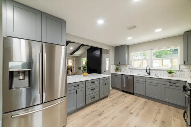 a kitchen with granite countertop a sink stainless steel appliances and window