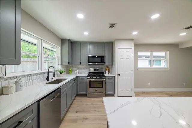 a view of a kitchen with kitchen island a sink stainless steel appliances and cabinets