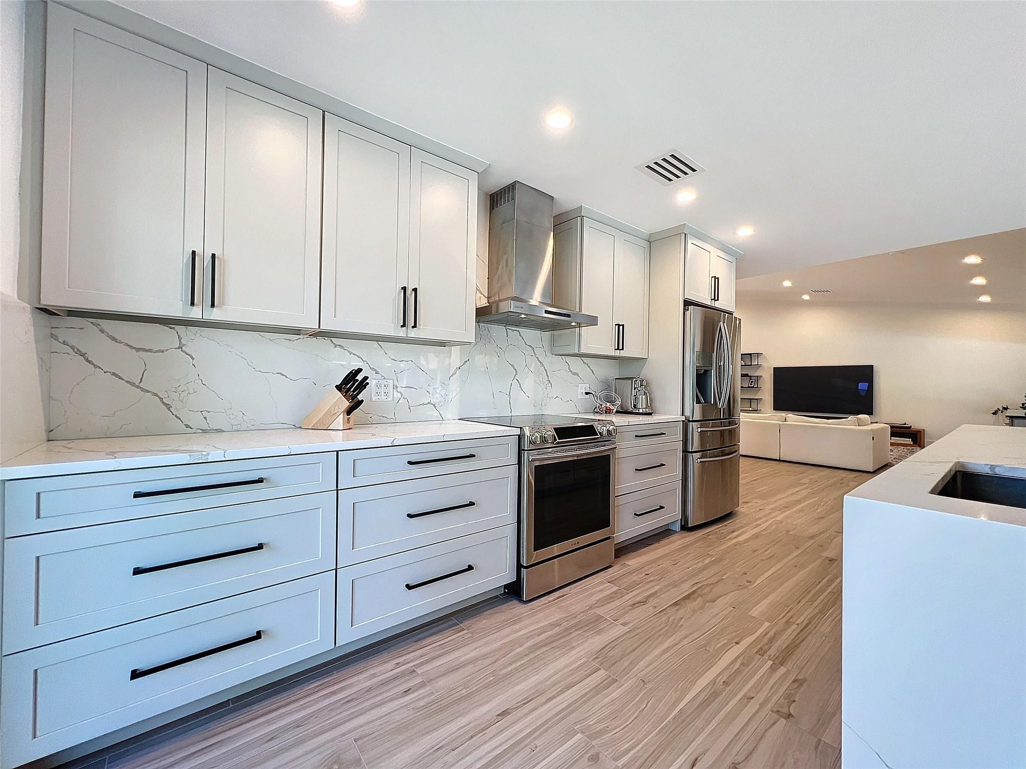 1501 Southwest 17th Street Boca Raton, FL 33486 - Photo 27 of 36 a kitchen with stainless steel appliances kitchen island granite countertop a stove a sink and a refrigerator