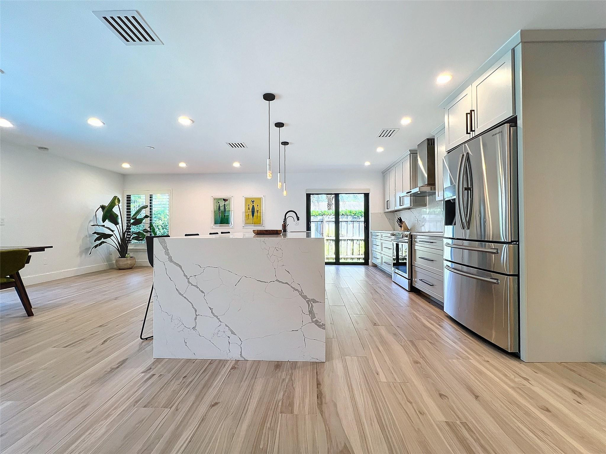 1501 Southwest 17th Street Boca Raton, FL 33486 - Photo 28 of 36 an open kitchen with stainless steel appliances kitchen island wooden floors and center island