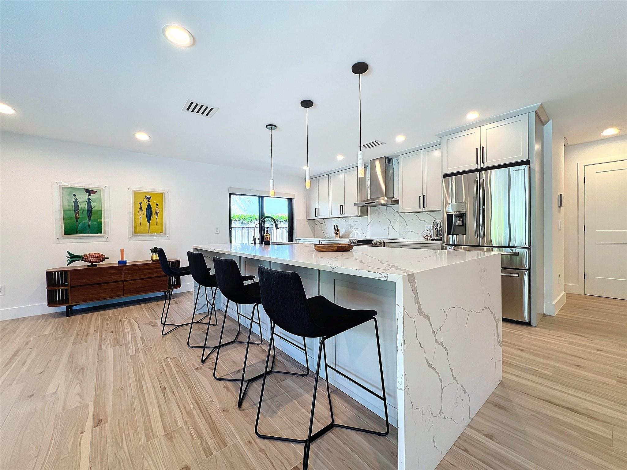 1501 Southwest 17th Street Boca Raton, FL 33486 - Photo 10 of 36 a kitchen with stainless steel appliances kitchen island granite countertop a sink a stove a refrigerator and white cabinets with wooden floor