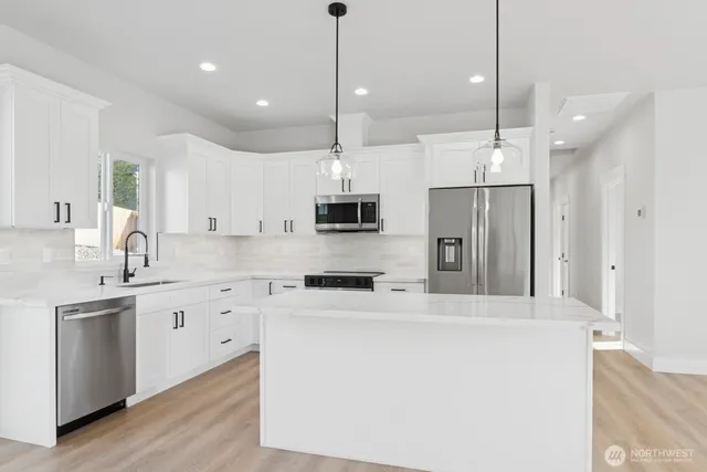 a kitchen with stainless steel appliances kitchen island a sink a stove a refrigerator and cabinets