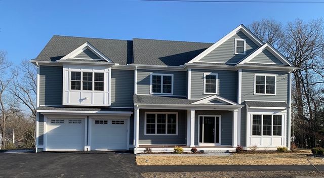 a view of a house with a yard plants and large tree