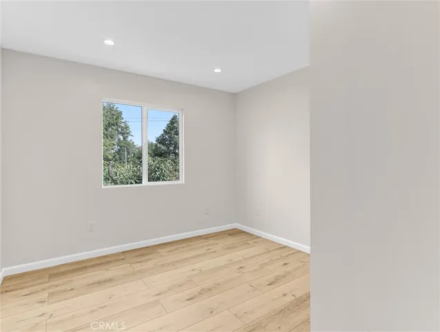an empty room with wooden floor and window