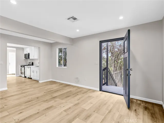 a view of empty room with wooden floor and fan