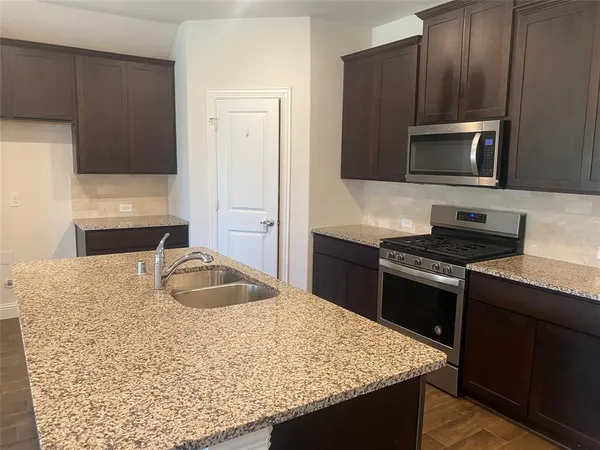 a kitchen with granite countertop wooden cabinets and stainless steel appliances