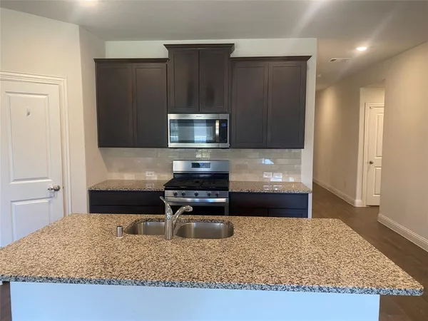 a kitchen with kitchen island granite countertop wooden cabinets and a sink