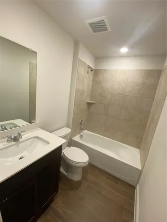 a bathroom with a bathtub shower sink vanity mirror and toilet