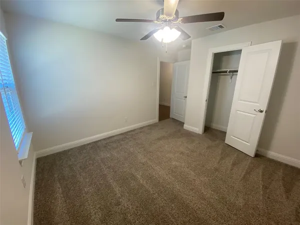 an empty room with a bathroom and a fan