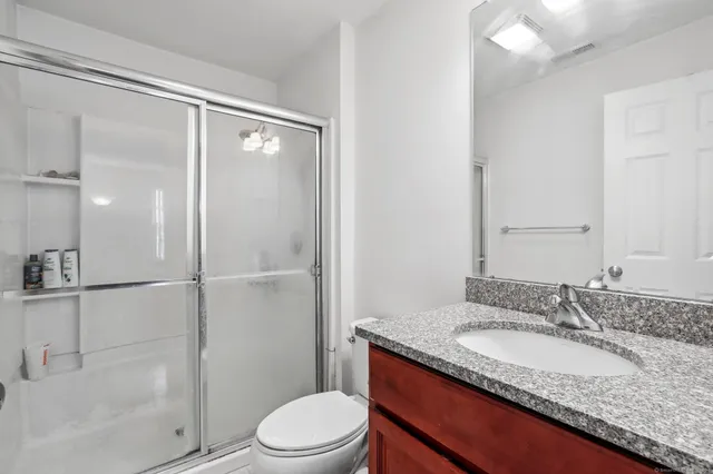 a bathroom with a granite countertop sink toilet and shower