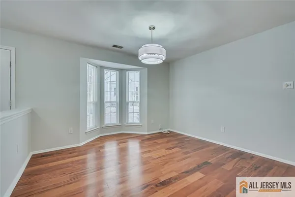 a view of an empty room with wooden floor and windows