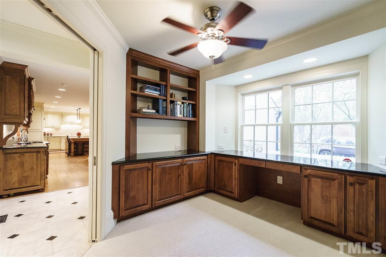 3202 Birnamwood Road Raleigh, NC 27607 - Photo 14 of 25 a view of a kitchen with kitchen island a sink wooden floor and a large window