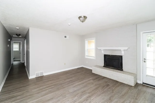 an empty room with wooden floor and fireplace