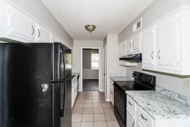 a kitchen with granite countertop a refrigerator and a sink