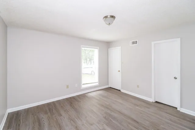 an empty room with wooden floor and windows