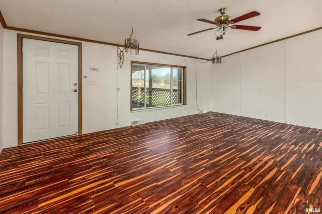 a view of empty room with wooden floor and fan