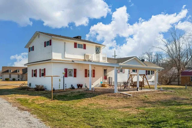 a view of a white house with a yard and lawn chairs