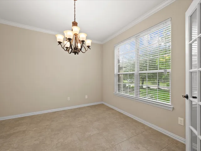 a view of an empty room with a window and chandelier fan
