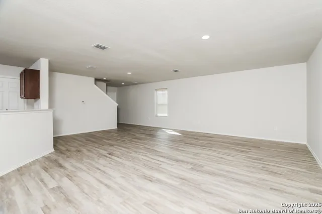 a view of an empty room with wooden floor and cabinets