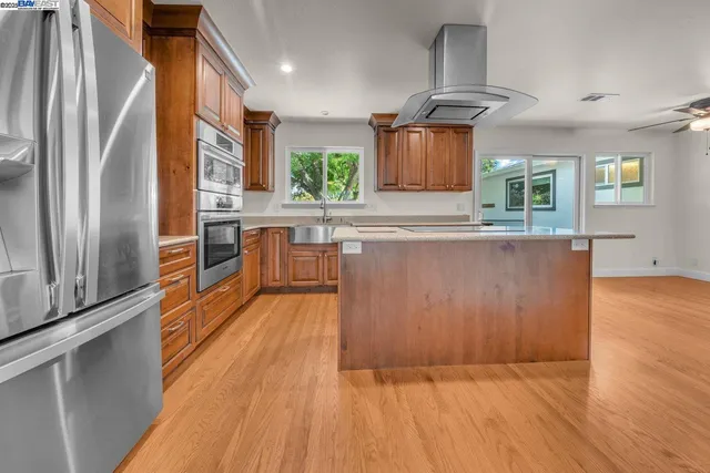 a kitchen with stainless steel appliances granite countertop a refrigerator a stove and a wooden floors