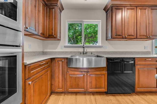 a kitchen with stainless steel appliances granite countertop wooden cabinets a sink and a window