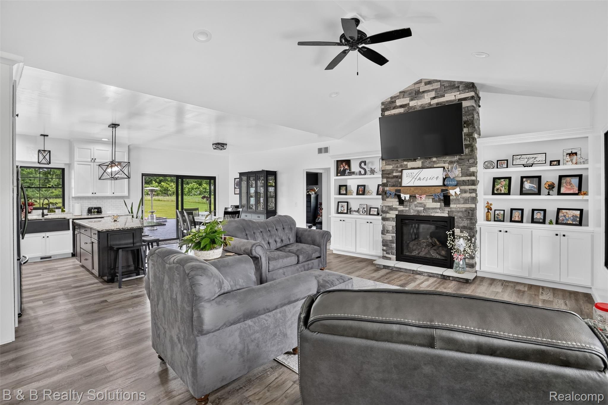 6204 Fish Lake Road North Branch, MI 48461 - Photo 8 of 79 Spacious living area featuring vaulted ceilings, wood-finish flooring, and a stone-clad fireplace with built-in shelving