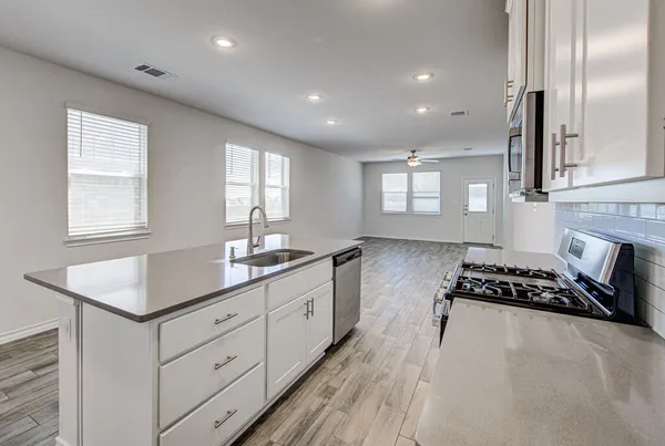 a kitchen with granite countertop a stove a sink a refrigerator and window