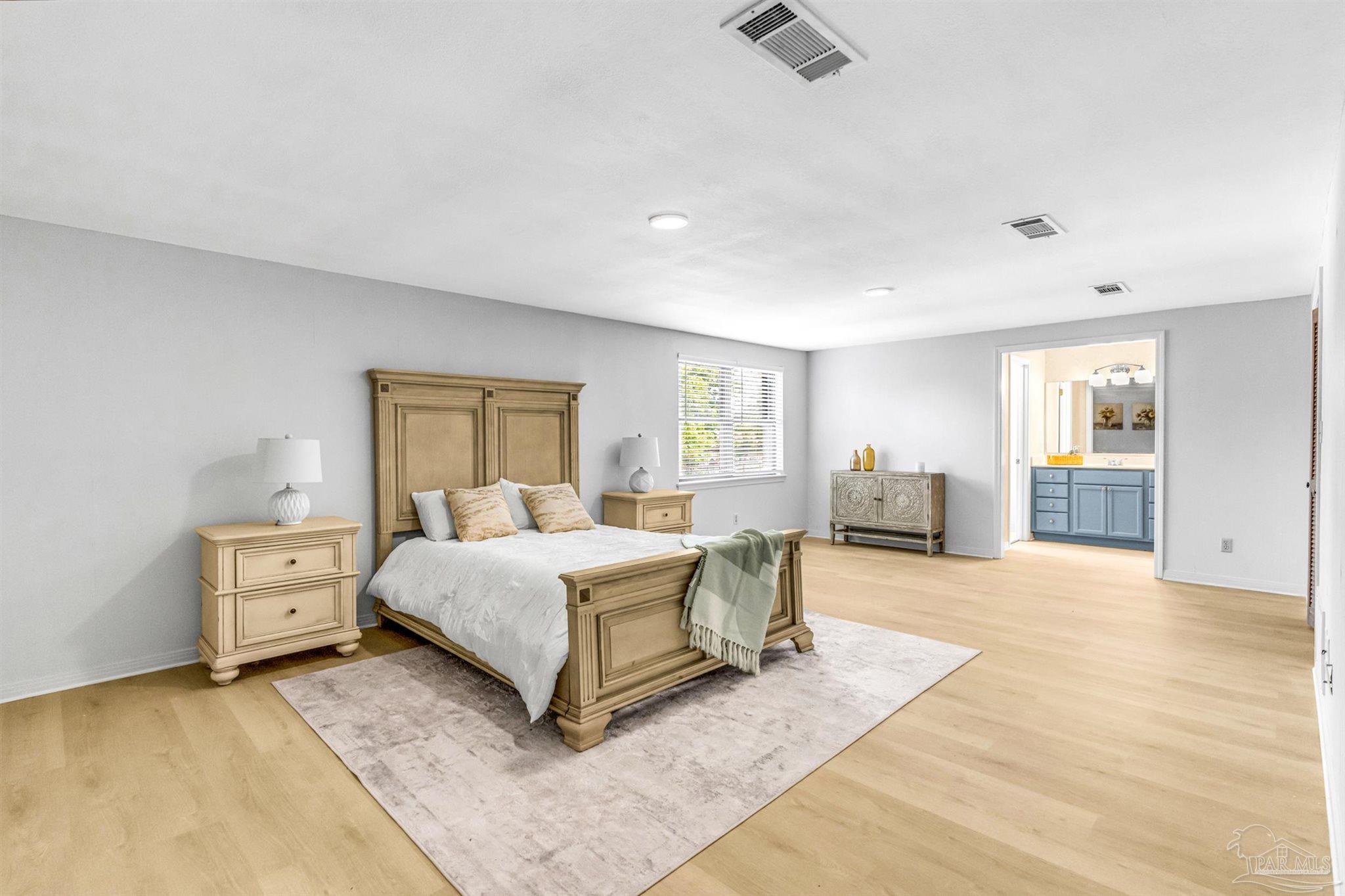 6912 Kitty Hawk Drive Pensacola, FL 32506 - Photo 41 of 61 a spacious bedroom with a bed a table and painting on the wall