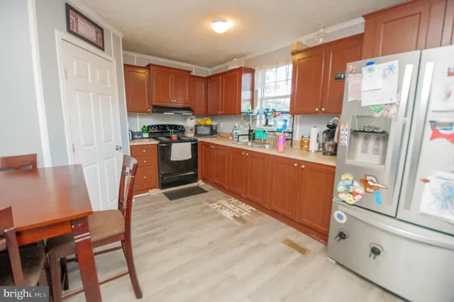 a kitchen with stainless steel appliances a refrigerator a sink a stove a table and chairs