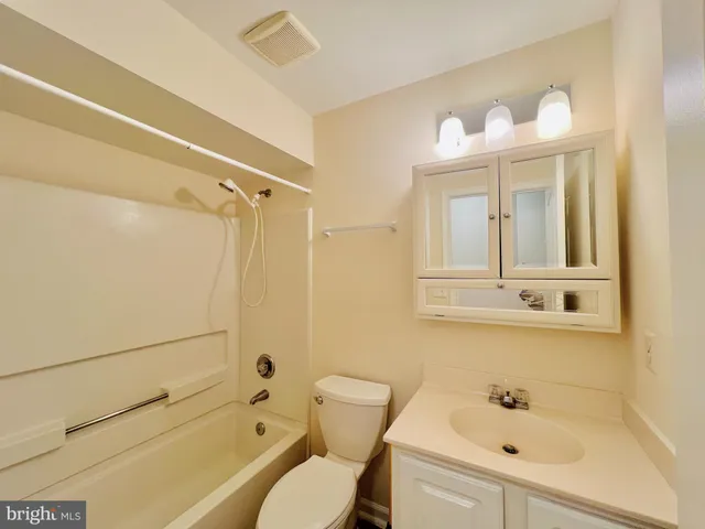 a bathroom with a bathtub shower sink vanity and toilet