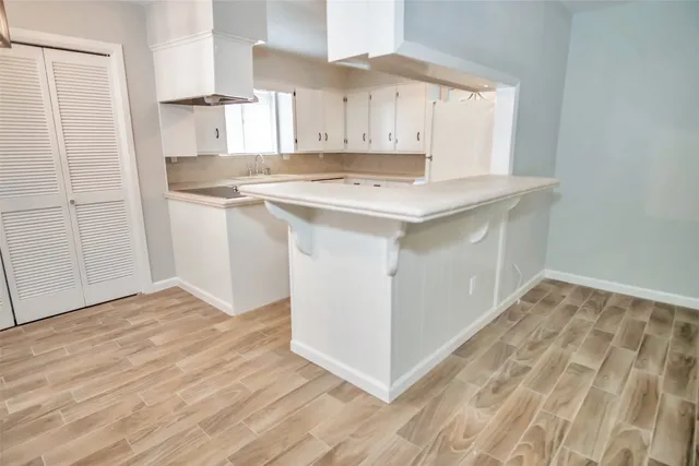 a kitchen with white cabinets and a stove with wooden floor