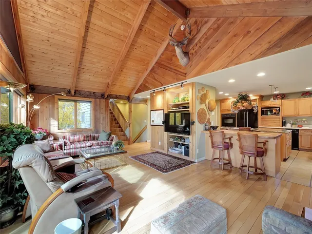 a living room with furniture a flat screen tv and floor to ceiling window