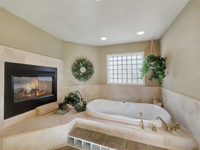 a bathroom with a tub a potted plant and a window