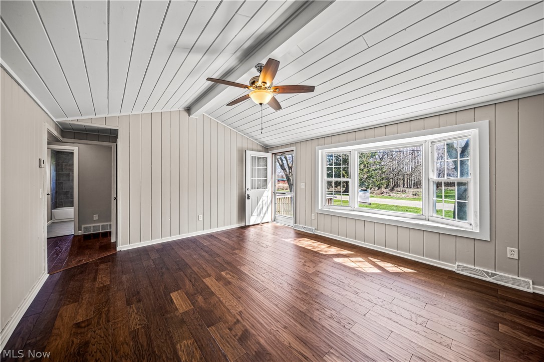 3395 Maple Road Jefferson, OH 44047 - Photo 3 of 36 Empty room featuring dark hardwood / wood-style flooring, ceiling fan, and vaulted ceiling with beams