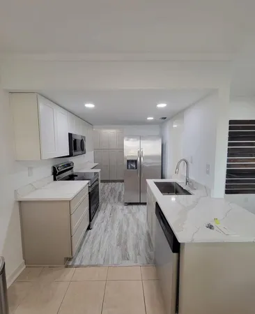 a kitchen with a sink a counter top space stainless steel appliances and cabinets