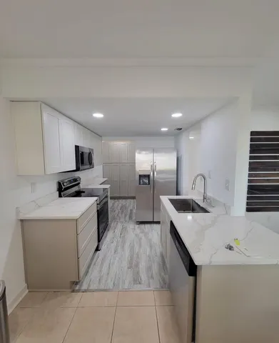 a kitchen with a sink a counter top space stainless steel appliances and cabinets