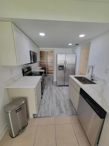 a kitchen with granite countertop a sink a counter top space stainless steel appliances and cabinets