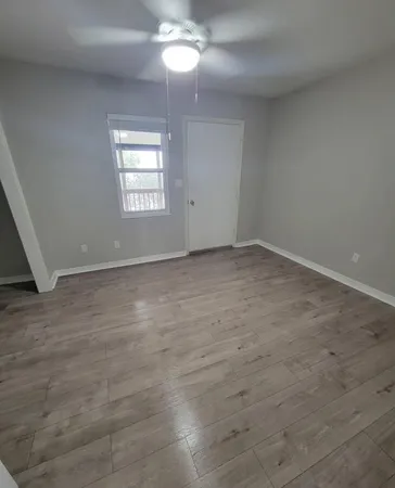 an empty room with windows and ceiling fan